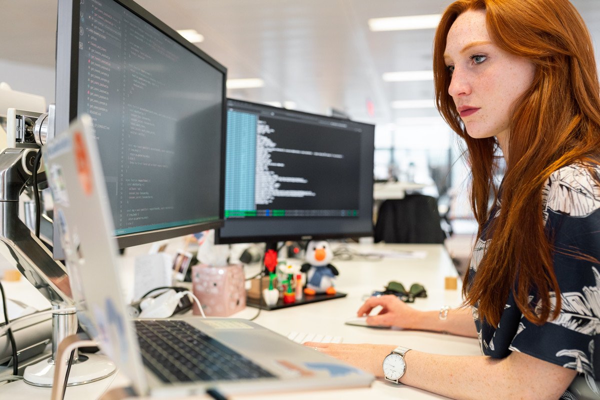 Woman looking at two computer screens doing software testing
